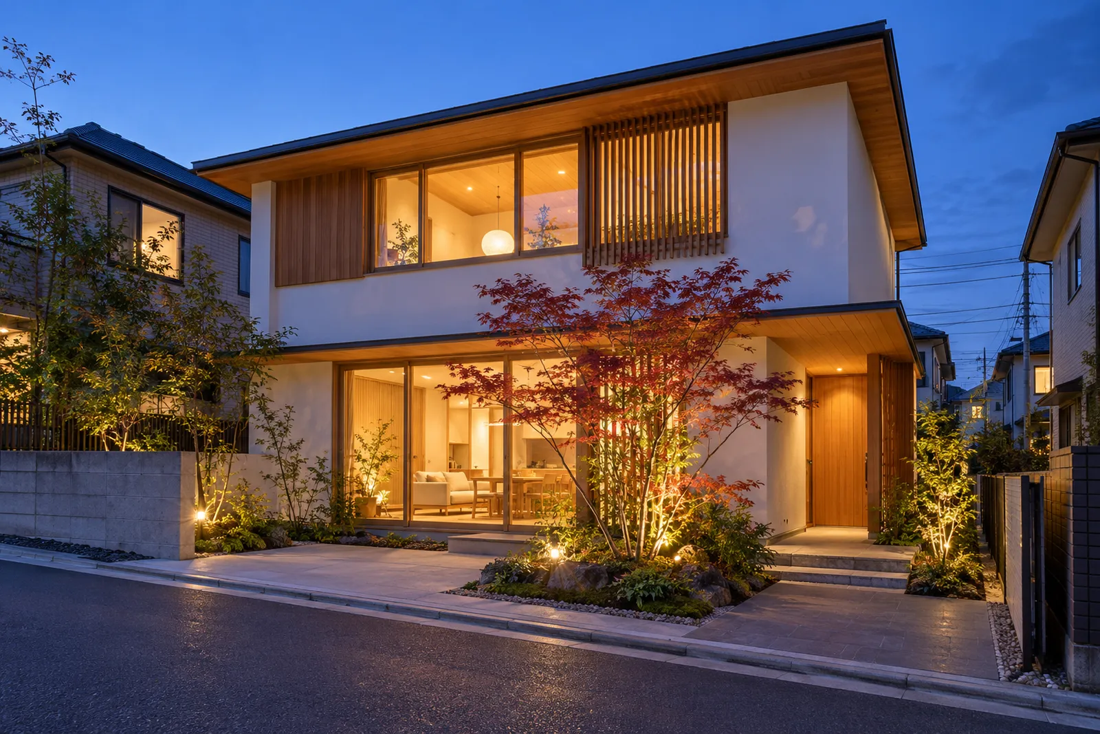 夕方、窓に明かりがついた二階建ての住宅